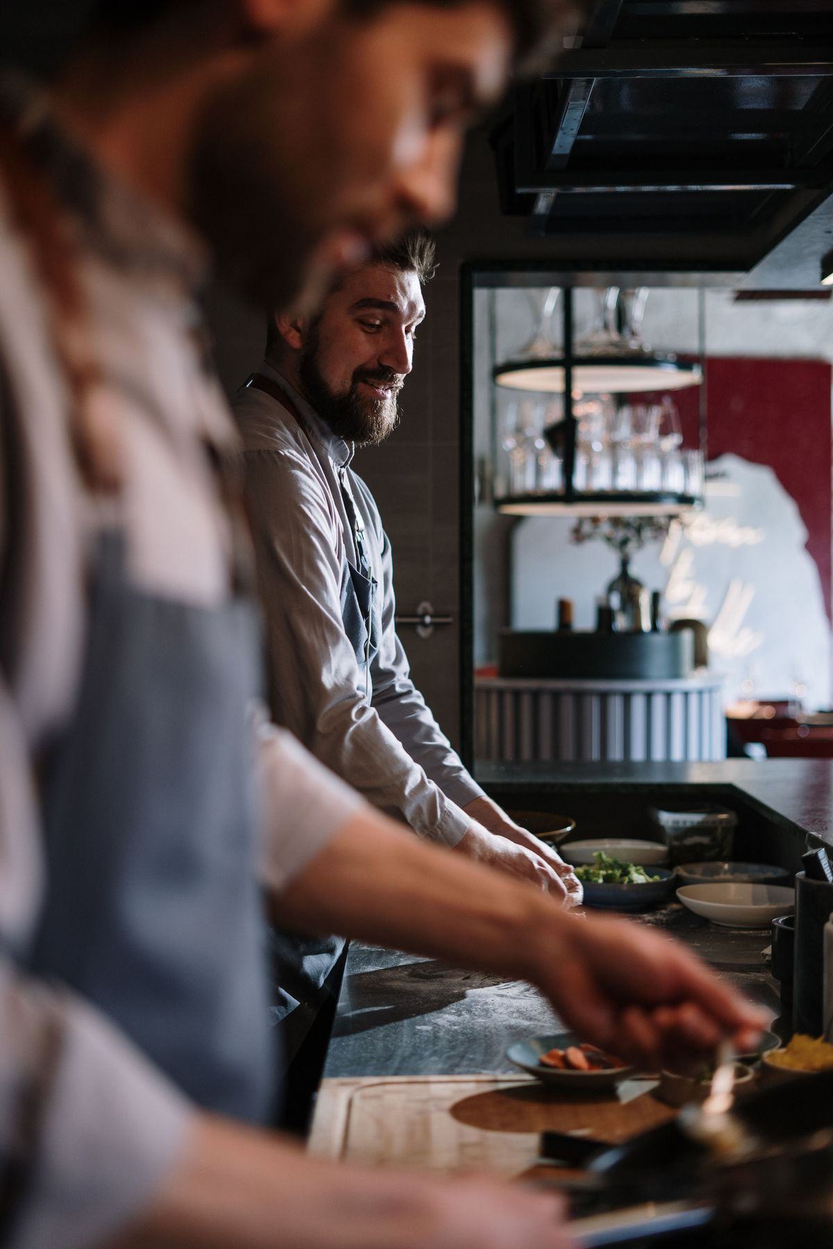 Two cooks working a restaurant pass in low light