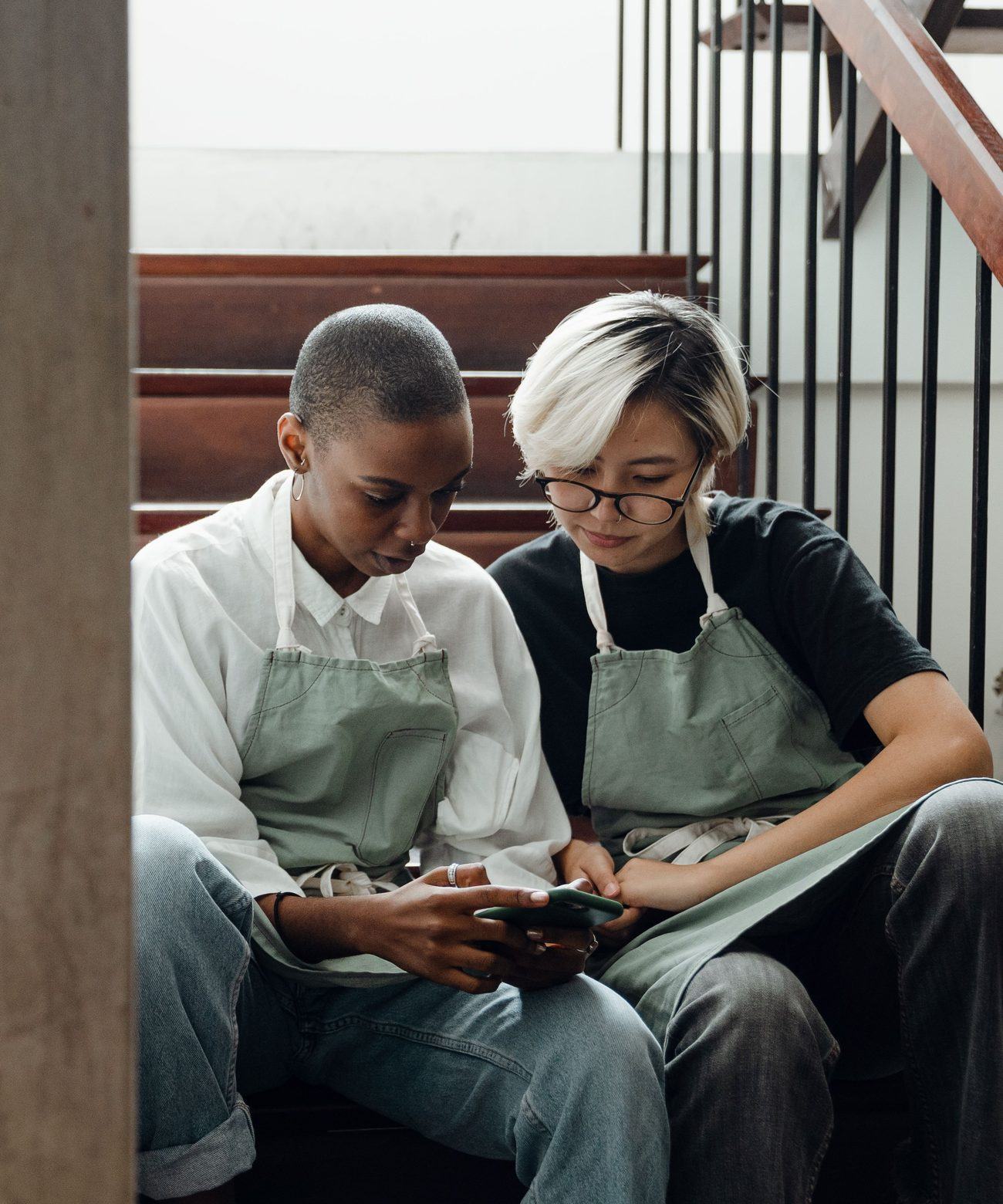 Two restaurant staff in aprons looking at a phone together between shifts